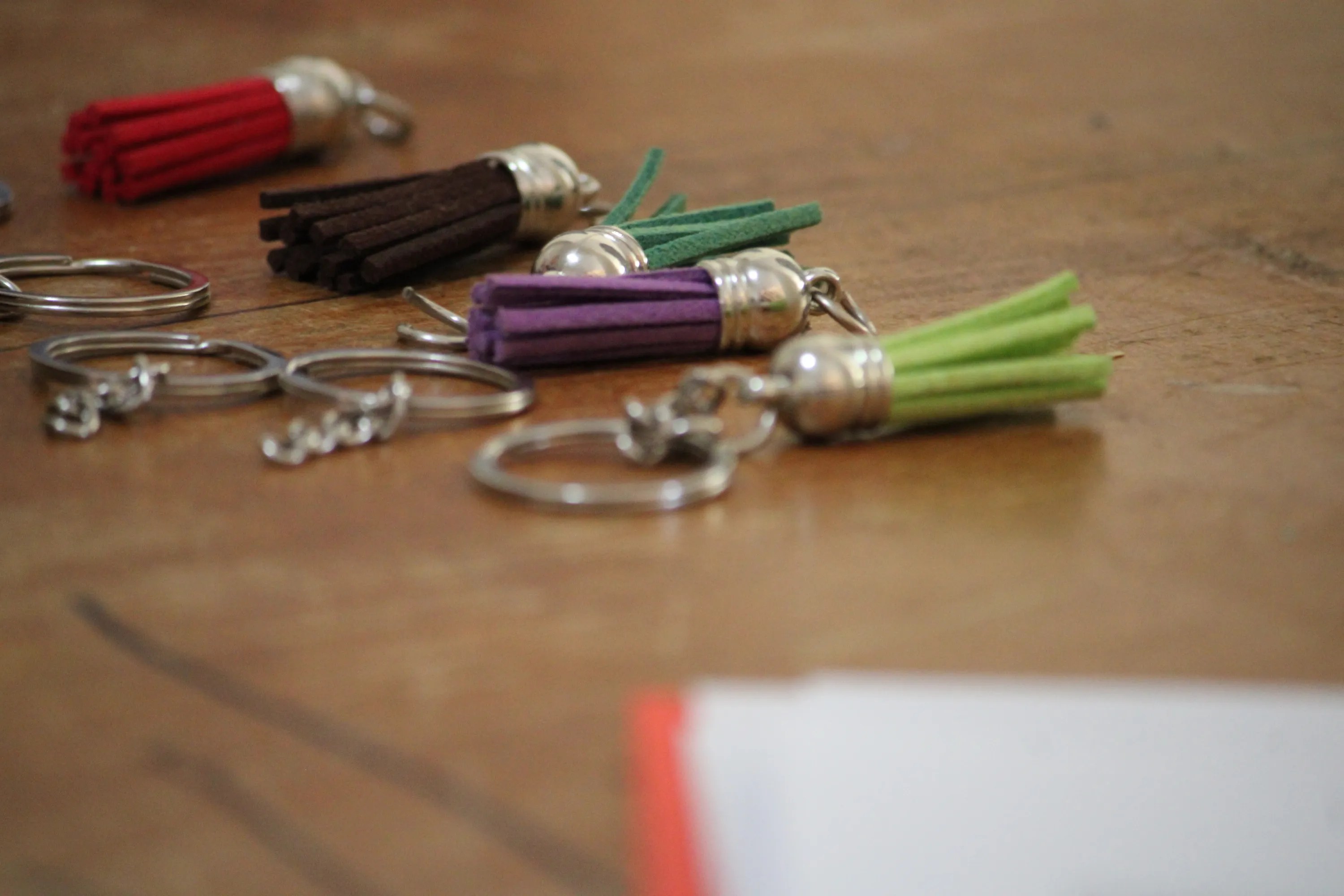 Coloured suede tassel keychains laid out on a wooden desk