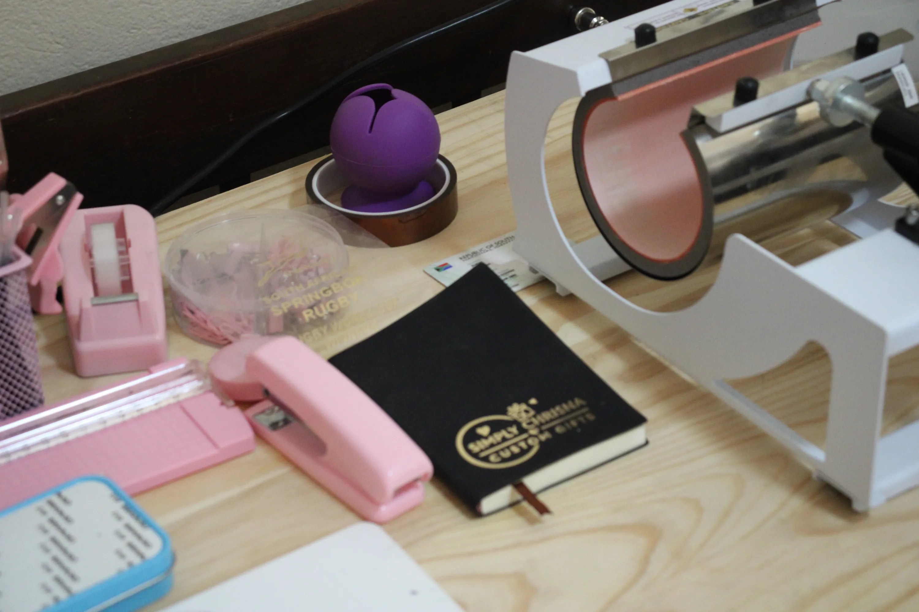 Chrisna's craft desk with tape, hole punch, notebook and heat press in the background